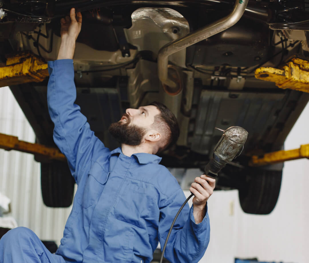 Service employee holding a light working on the undercarriage of a vehicle